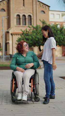 Woman supporting smiling friend using wheelchair
