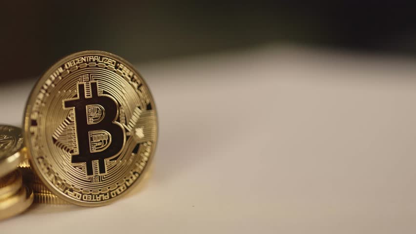 golden bitcoin coin in smooth motion establishment pan shot, BTC coin in depth of field on white blurry background