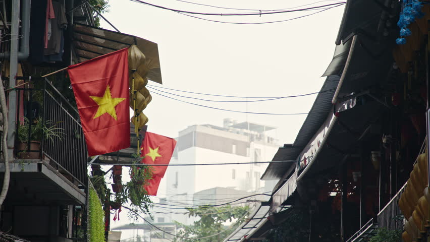 Stroll through bustling alleys adorned with bright red Vietnam flags, showcasing local architecture and daily life. Discover the rich culture and atmosphere of Vietnam.