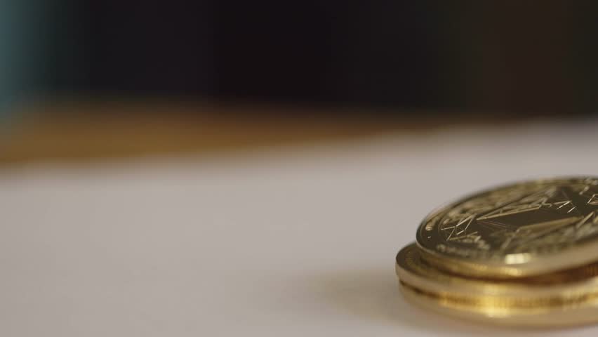 batch of physical bitcoins in bright light, shining gold. Display BTC establishment pan shot, coin in depth of field on white blurry background