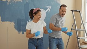 Middle-aged hispanic couple joyfully dancing while renovating their living room together, celebrating family and love in a cozy home setting with painting supplies around. - Powered by Shutterstock - Get 15% off with code: PIKWIZARD15
