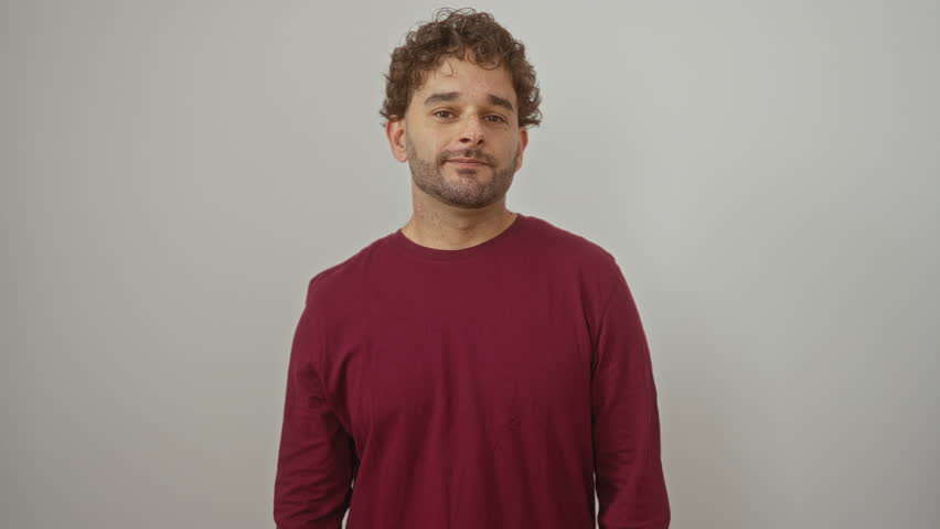 Young hispanic man standing with t-shirt, mouth and lips silent and shut, finger gesture of zip over white isolated background, secret communication concept