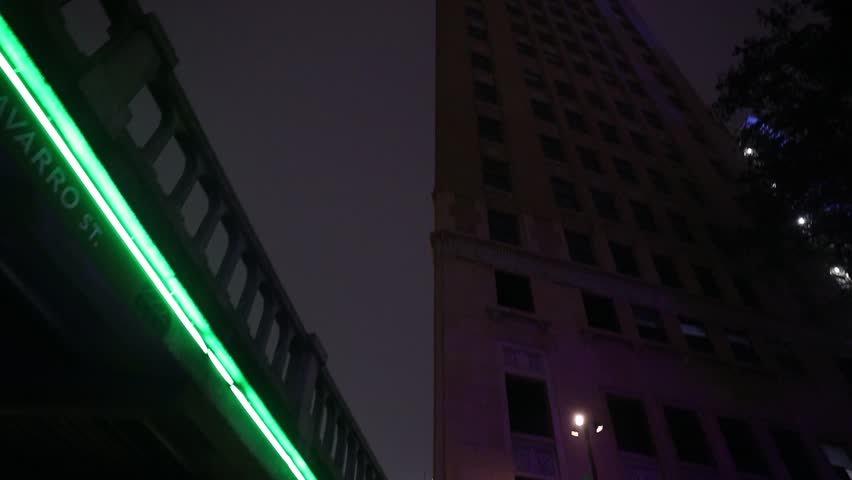 A dark, moody shot tilts upward, revealing a towering building shrouded in thick fog, its faint lights barely piercing the night