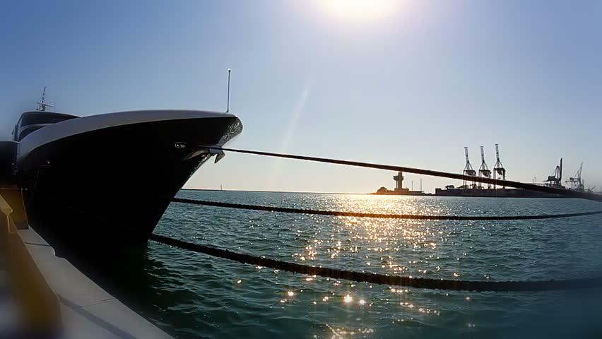 Blue sky. The motor yacht is moored at the pier. The sun shines on the water