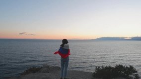 A brunette woman with a Russian flag on her shoulders stands on a rocky seashore at sunset. Gives independence, patriotic holiday concept. - Powered by Shutterstock - Get 15% off with code: PIKWIZARD15