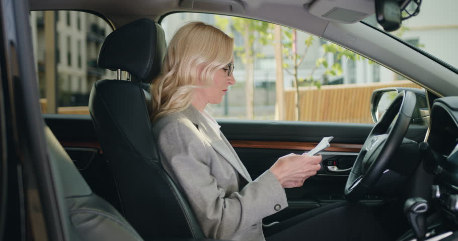 Business woman driver in formal clothes counts the money, count cash financial profits, while sitting in luxury car. Concept of fuel price increase