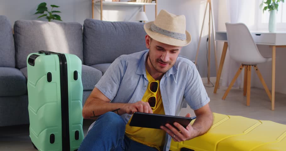 Happy traveller tourist in hat booking cheap flight tickets online for favourite destination, ready for summer trip holiday, luggage bag vacation travel, suitcase for journey, leaving moving, planning