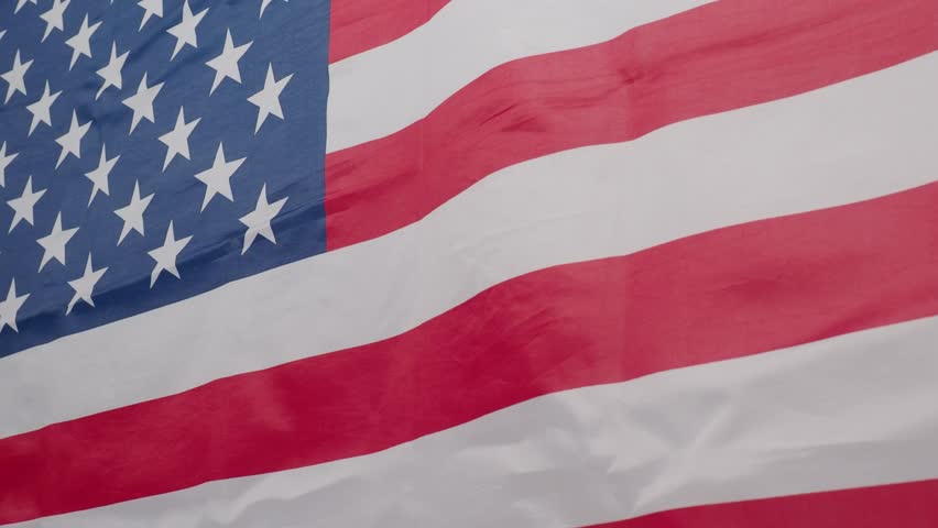 United States of America flag. Close up of United States flag waving in the wind. The stars and stripes ripple showing the patriotic red white blue colors. USA nation flag Symbol of freedom waving.