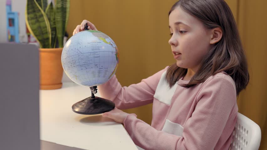 Cute girl sitting at laptop in her room. Child studying online concept. E-learning from home.