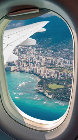 Panoramic aerial view of the coastal city of Honolulu on Oahu, Hawaii, United States of America. Seen from above through the window of an airplane flying over the area. Vertical and portrait format