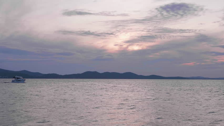 Boat moving in choppy mediterranean ocean under cloudy dusk sky. Zadar, Croatia