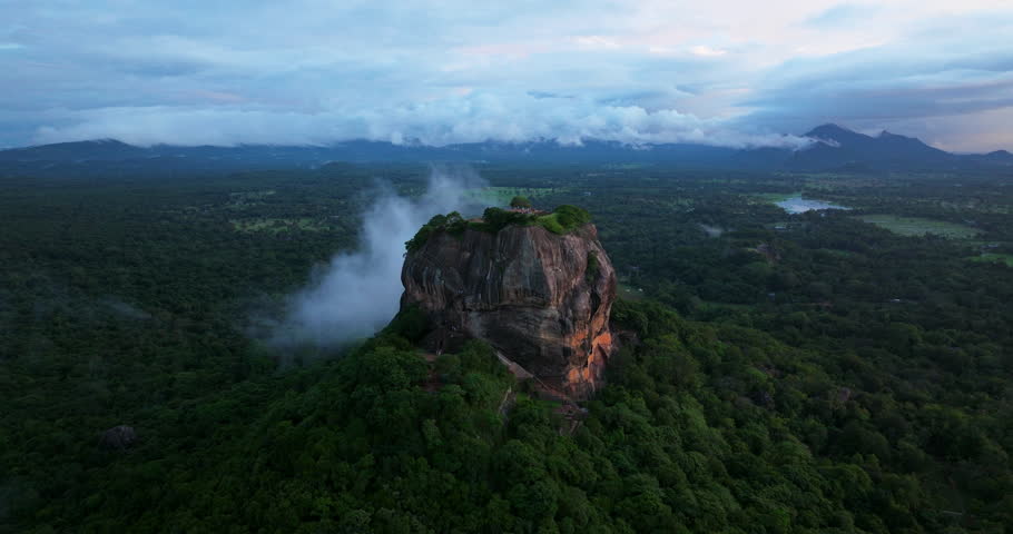 Sigiriya (Lion Rock), Dambulla, Sri Lanka - A Stunning View of an Ancient Rock Fortress Veiled in Mist at Sunset - Orbit Drone Shot