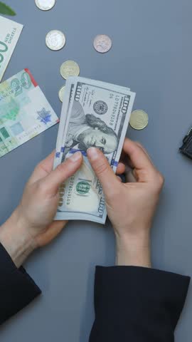 Woman holding pile of american one hundred dollar bills. Female hands counting cash money, close up. Hands count dollars. Vertical video