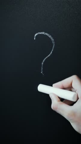 Hand is painting "question mark" on chalkboard. Question mark on blackboard. Male hand drawing question mark. Vertical video