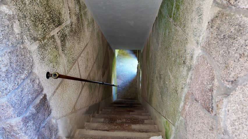 Stone staircase in Sintra's Quinta da Regaleira, Portugal with rustic walls and bright light at the end