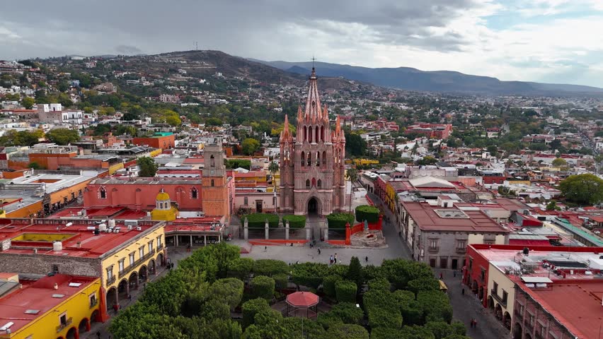 San Miguel Arcangel Parish Church with city and mountains in the background in San Miguel de Allende, Mexico. Drone shot approaching the church