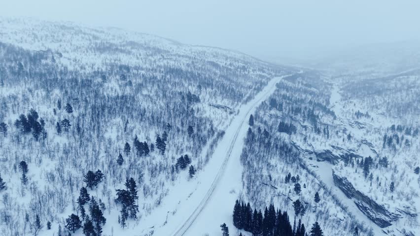 Snow-covered landscape in Norway with a road winding through the mountains