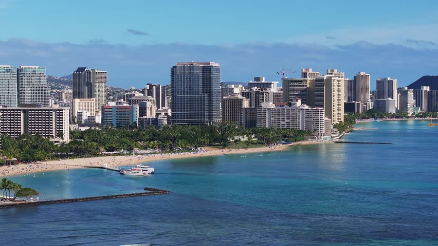 A slow pan of Waikiki Beach in Oahu, Hawaii, with Diamond Head crater, turquoise waters, surfers, boats, and Honolulu
