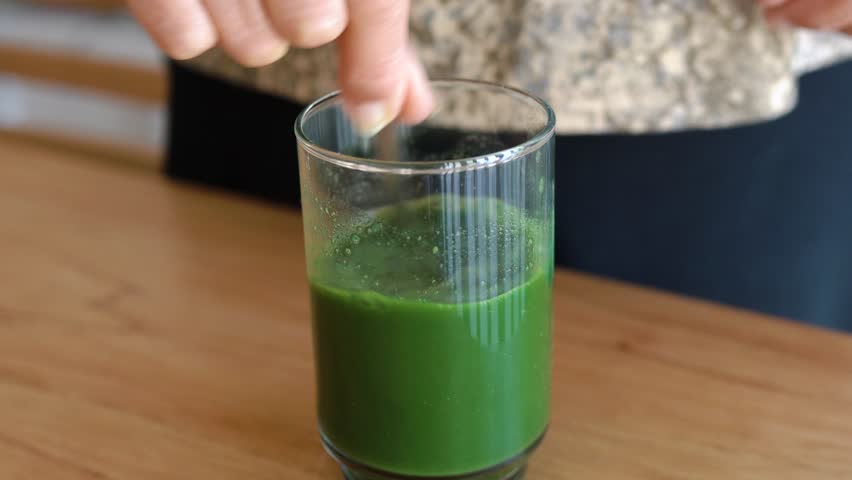 Mixing spirulina powder with natural green juice for detox.
