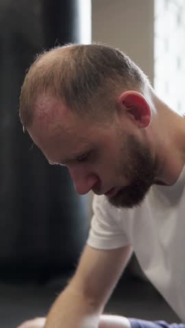 Boxer man tired and sweaty sits on bench with serious look after active training. Willpower and motivation. Veritical video. Slow motion video.