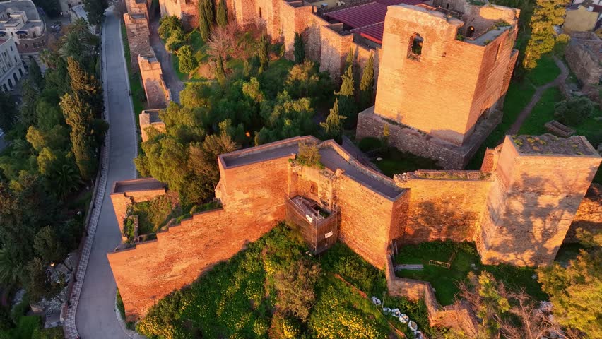 Malaga fortress in the morning golden light, aerial revealing shot, drone shot of Andalusian city of Malaga, tourism in Andalusia, Spain, Castillo de Gibralfaro in Malaga