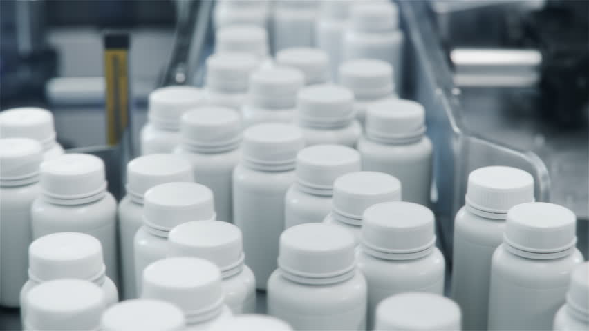 Close-up of Plastic Medicine Bottles with Pills on Conveyor at Pharmaceutical Production Plant. Medication Manufacturing Process at Pharmaceutical Drug Factory 