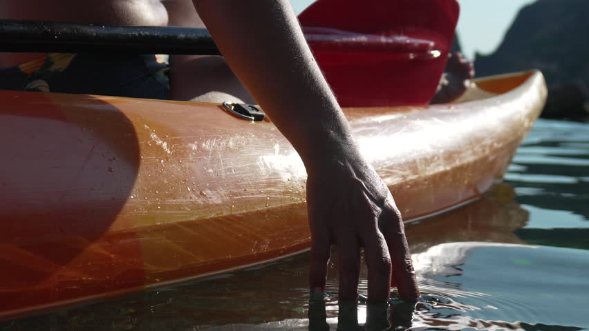 Kayaking Hand Water - Person kayaking in a lake, reaching out to touch the water with their hand.