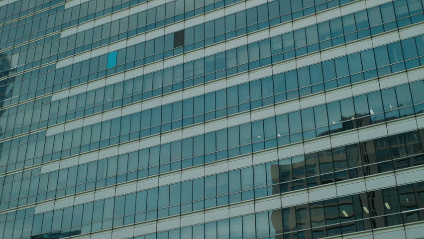 Contemporary high-rise office building with reflective glass facade, showcasing geometric design and urban architecture in Bangkok, Thailand.