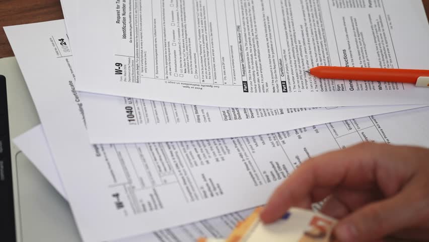 Businessman sitting at wooden table reconciles accounts by tallying 50-euro banknotes and reviewing tax paperwork pertained to household office expenses slow motion