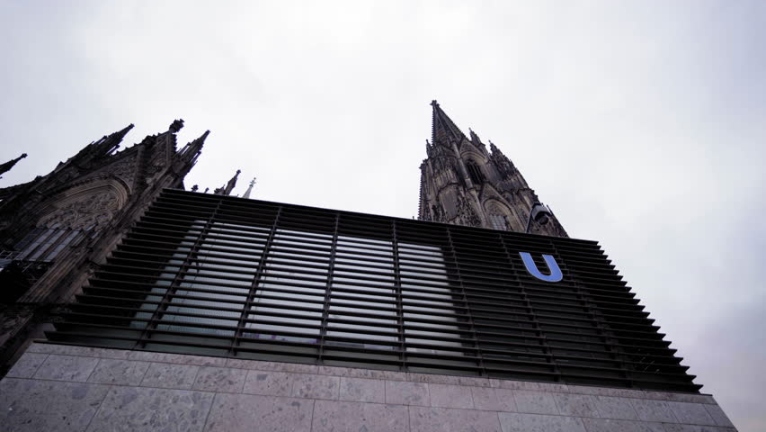 Striking contrast between the historic Cologne Cathedral and a modern subway lift entry, showcasing the blend of old and new architecture in Cologne, Germany.