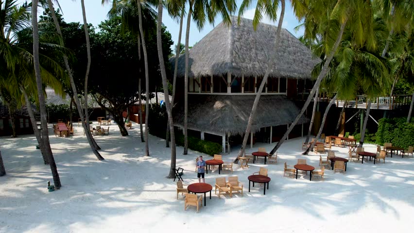 Beachfront restaurant at Maldives luxury tropical resort with palm trees and blue water
