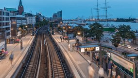 Aerial day to night transition timelapse of trains arriving at Landungsbrucken station in Hamburg, Germany. People boarding the subway, panoramic view with Elbphilharmonie, harbor and marina - Powered by Shutterstock - Get 15% off with code: PIKWIZARD15