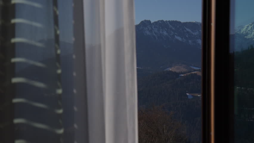 The Window Curtain Unveils a Scenic View of the Bavarian Alps in Germany - Panning Shot