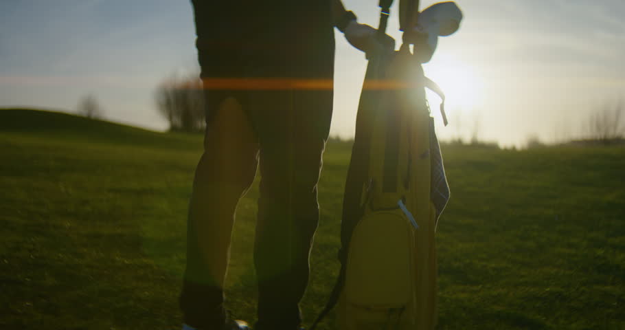 Pro Golfer Shoulders Golf Bag at Sunny Course - Low Angle Slow Motion
