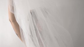 Camera tracks in as a veil falls away, it reveals a bride with a beautiful floral crown. Her elegant white dress complements her serene expression, adding an air of tranquil beauty to the scene. - Powered by Shutterstock - Get 15% off with code: PIKWIZARD15