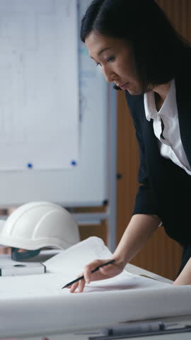 Focused woman architect carefully draws a blueprint, planning a building project