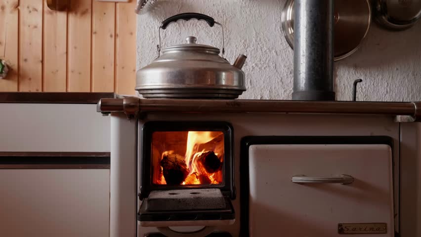 A wood-burning stove with flames inside, used in an old Swiss house for heating