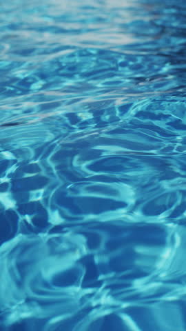 Ripples on the water of the pool; transparent; sparkling; inviting surface of the water in motion; view from above. slow motion and looped vertical video.
