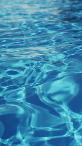 Ripples on the water of the pool; transparent; sparkling; inviting surface of the water in motion; view from above. slow motion and looped vertical video.