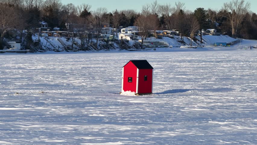 Ice fishing hut on frozen lake in the middle of winter - 4K Drone Video