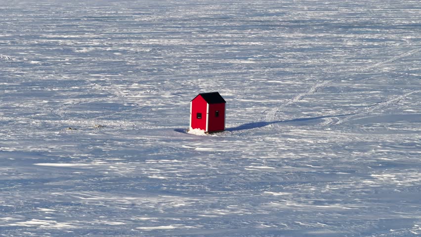 Ice fishing hut on frozen lake in the middle of winter - 4K Drone Video