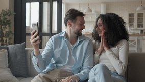 Young Interracial Couple Smiling, Enjoying Fun Video Call Together On Cozy Sofa - Powered by Shutterstock - Get 15% off with code: PIKWIZARD15