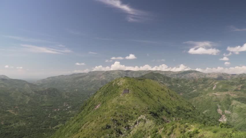 Slow motion pan across the green Haitian mountains under a vibrant blue sky seen from Laferriere Citadel