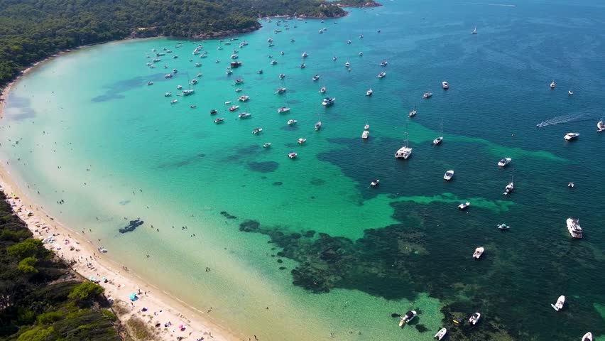 Îles d'Hyères - France Notre Dame Beach, Cote d´Azur, France, aerial view. Drone circling above the bay. Yachts and boats in the middle of the bay. Famous travel destination in South of France.