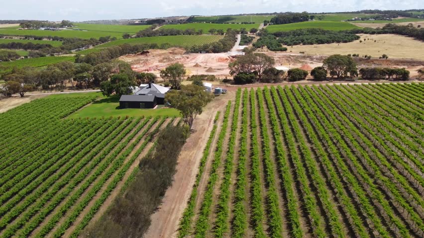Aerial view of a quarry and McLaren Vale vineyards in South Australia. The drone footage captures colorful clay and dirt piles, machinery, and a backdrop of lush vineyards and farmland.
