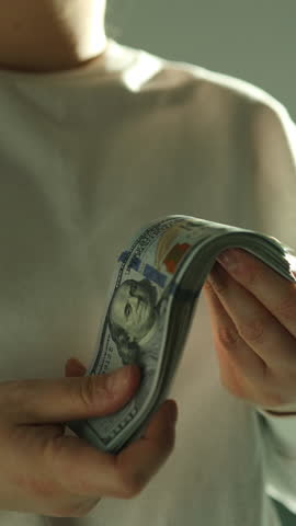 Woman counting hundred-dollar bills while reviewing tax documents. Financial planning and tax preparation concept.World economy. Currency exchange. Cash payment. High quality FullHD footage