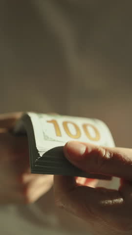 Woman counting hundred-dollar bills while reviewing tax documents. Financial planning and tax preparation concept.World economy. Currency exchange. Cash payment. High quality FullHD footage