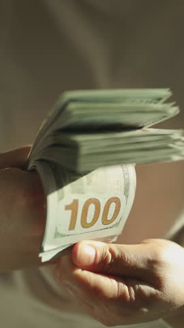 Woman counting hundred-dollar bills while reviewing tax documents. Financial planning and tax preparation concept.World economy. Currency exchange. Cash payment. High quality FullHD footage