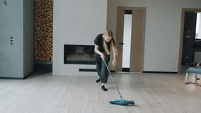 Teenage girl mopping the floor in a modern living room, moving energetically as if dancing while doing household chores. High quality 4k footage - Powered by Shutterstock - Get 15% off with code: PIKWIZARD15