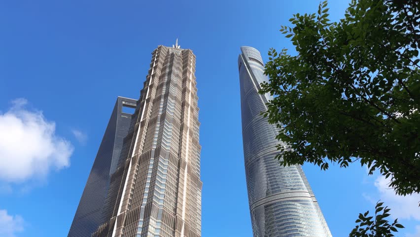 A stunning view of three iconic skyscrapers in Pudong, Shanghai: Shanghai Tower, Jin Mao Tower, and Shanghai World Financial Center under a clear blue sky.